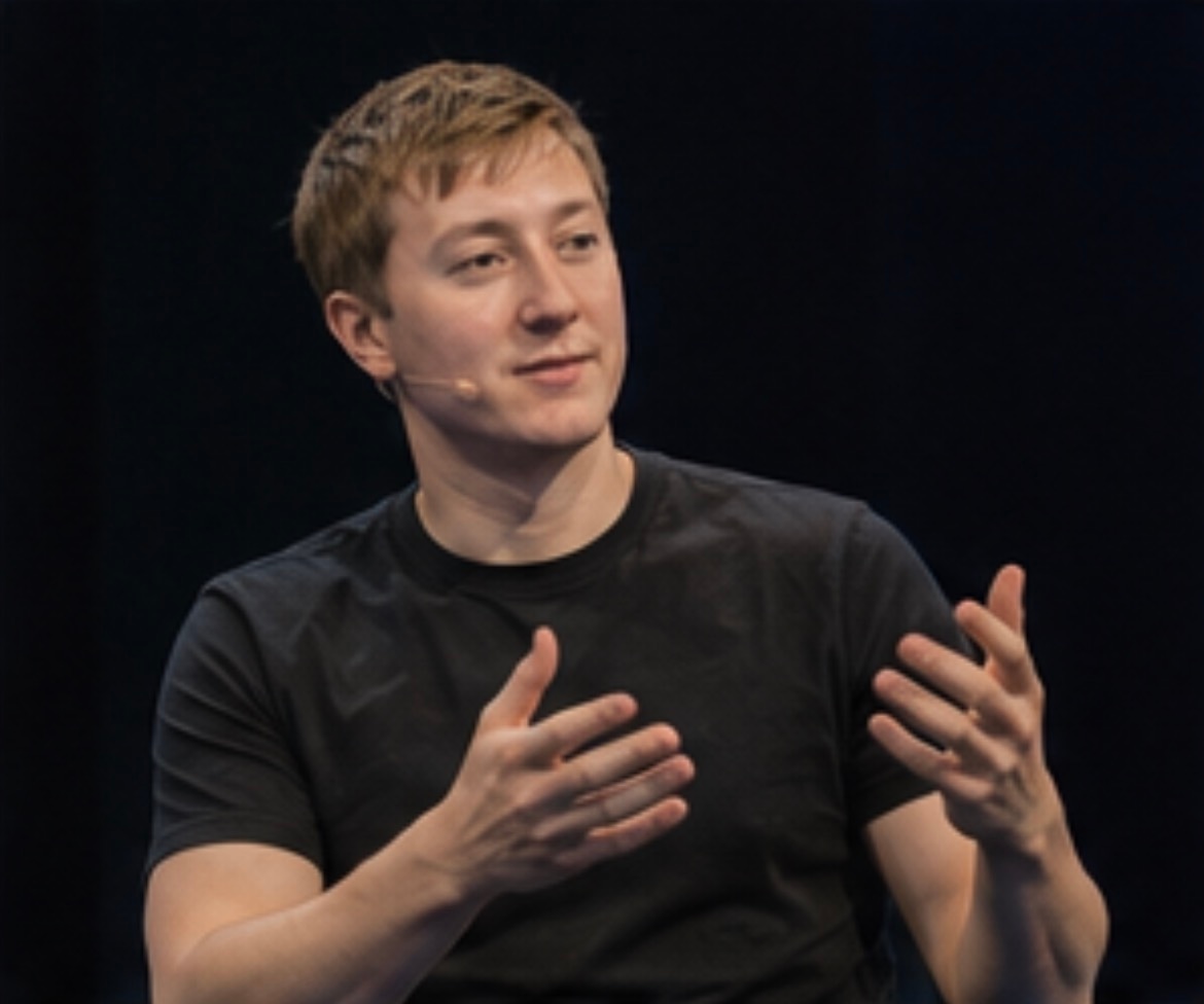 Moritz Zinecker speaking with a headset microphone on a dark stage