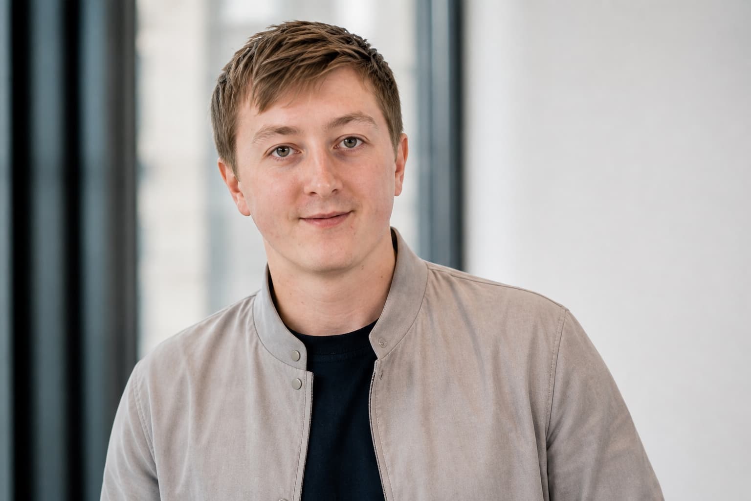 Moritz Zinecker in a light gray jacket in a bright office setting
