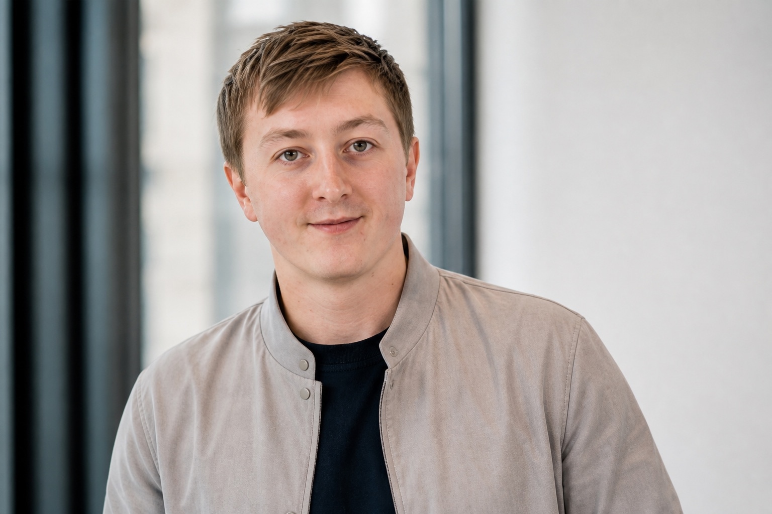 Moritz Zinecker in a light gray jacket in a bright office setting