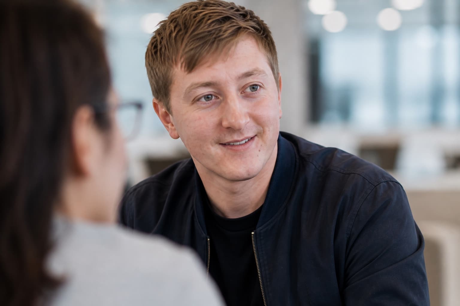 Moritz Zinecker smiling during a close conversation in an office setting