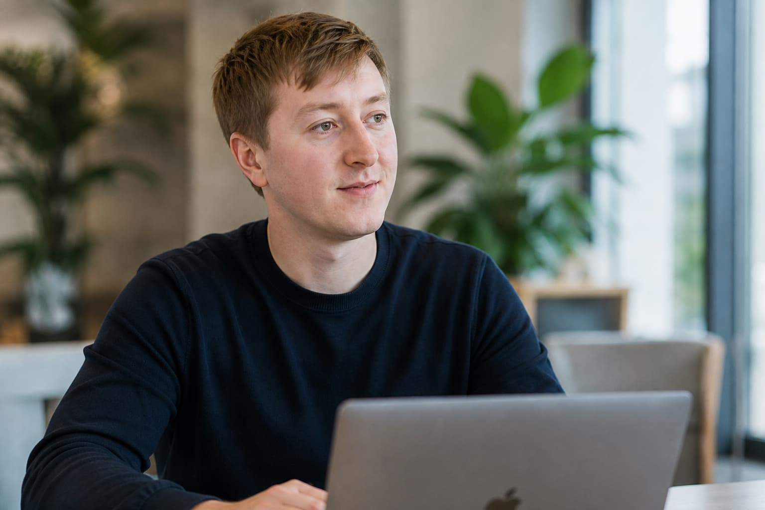 Moritz Zinecker seated at a table with an open laptop in a bright work setting