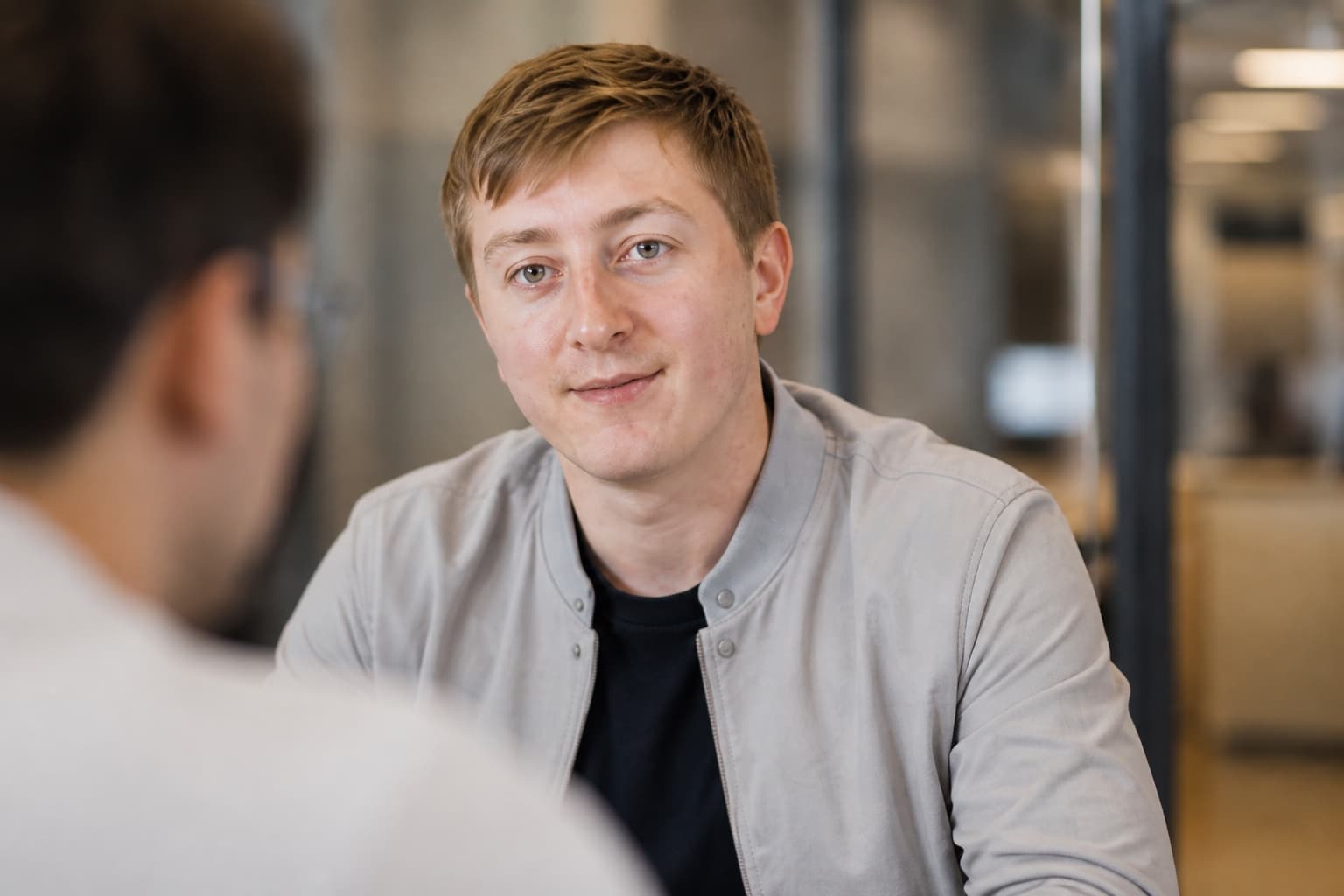 Moritz Zinecker in a light gray jacket during a seated office conversation
