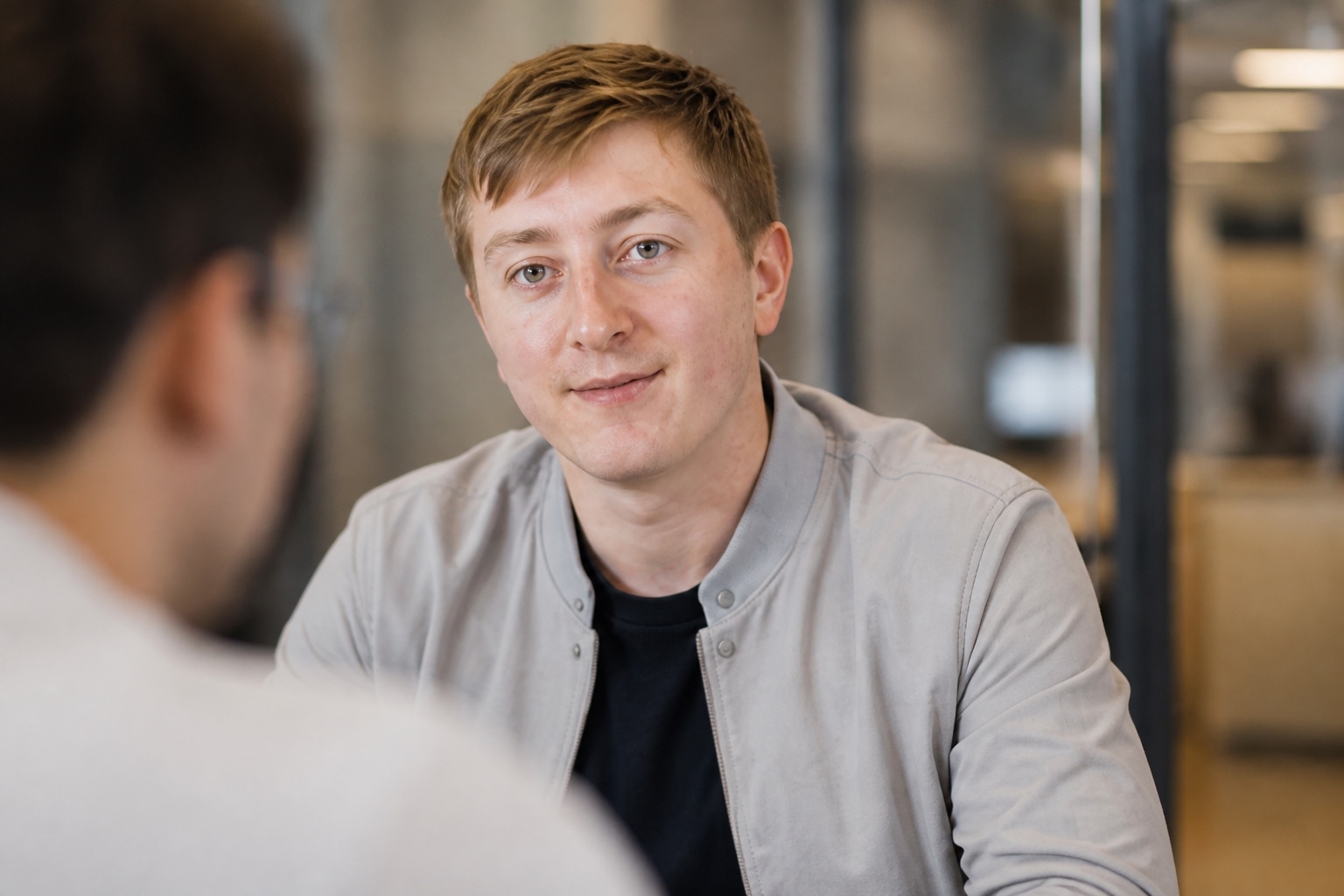 Moritz Zinecker in a light gray jacket during a seated office conversation