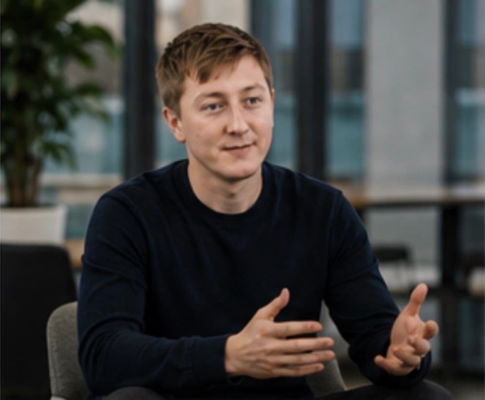 Moritz Zinecker speaking during a seated conversation in a modern work setting
