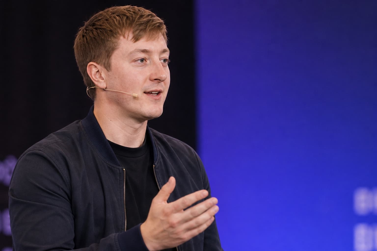 Moritz Zinecker speaking with a headset microphone on a blue-lit stage