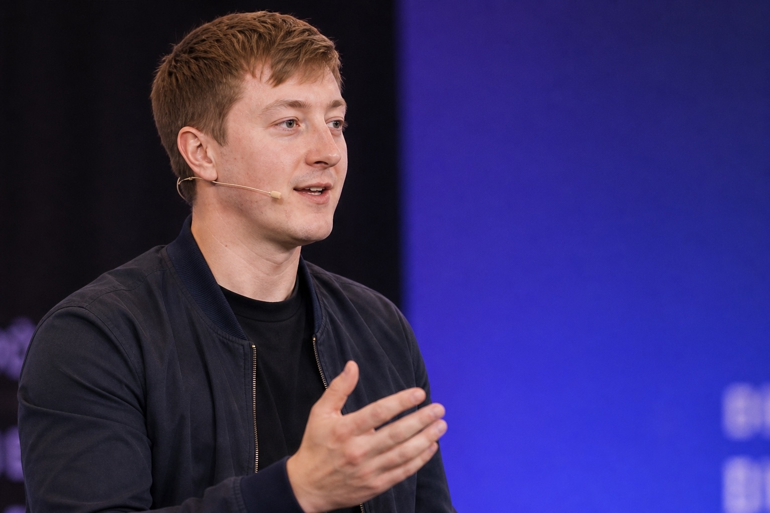 Moritz Zinecker speaking with a headset microphone on a blue-lit stage